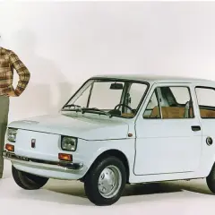 Para młoda pozuje obok białego Fiata 126p Bis.