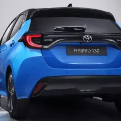 Niebieski hatchback Toyota Yaris IV z czarnym dachem i napisem HYBRID 130 z tyłu.