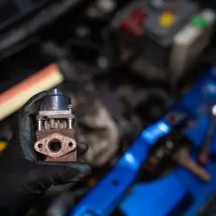 Zardzewiały zawór EGR w dłoni mechanika. Zepsuty EGR może powodować różne objawy, takie jak nierówna praca silnika czy zwiększone spalanie.