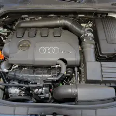 Silnik TFSI w Audi 8P, widok z góry. Widać pokrywę silnika z logo Audi, elementy układu dolotowego i filtry.