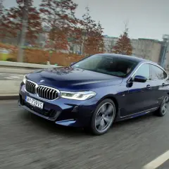 Granatowe BMW 640i sunie po miejskiej drodze, ukazując swoje eleganckie linie i sportowy charakter.