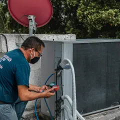 Technik sprawdza ciśnienie na zaworze rozprężnym klimatyzacji, używając manometrów.