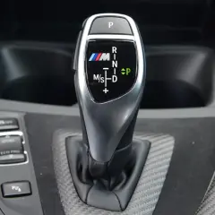 Oznaczenia automatycznej skrzyni biegów BMW M: P, R, N, D, M/S. Widoczny przycisk P i wybór trybów Sport/Eco Pro.