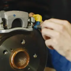 Mechanik pracuje nad tarczą hamulcową, sprawdzając stan układu hamulcowego.