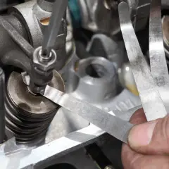 Precyzyjna regulacja zaworów silnika przy użyciu szczelinomierza. Mechanik sprawdza luz zaworowy.