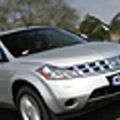 Srebrny Nissan Murano 3.5 V6 na drodze, z drzewami i innymi samochodami w tle.