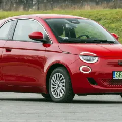 Czerwony fiat elektryczny 500 na tle zielonej skarpy.