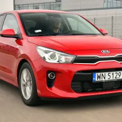 Czerwony **Kia Rio 4** w ruchu drogowym, z kierowcą za kierownicą.