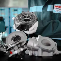 Mechanik w fartuchu Bosch Service prezentuje części turbosprężarki. Dowiedz się, ile kosztuje regeneracja turbiny i przywróć moc swojemu autu.