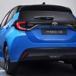 Niebieski hatchback Toyota Yaris IV z czarnym dachem i napisem HYBRID 130 z tyłu.