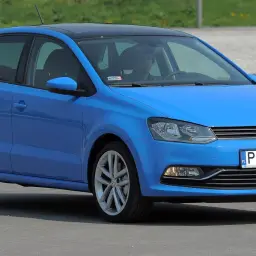 Niebieski VW Polo 2010 z czarnym dachem, zaparkowany na zewnątrz.