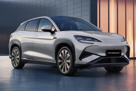 Elegancki, srebrny BYD Sealion 7 SUV stoi przed nowoczesnym budynkiem.