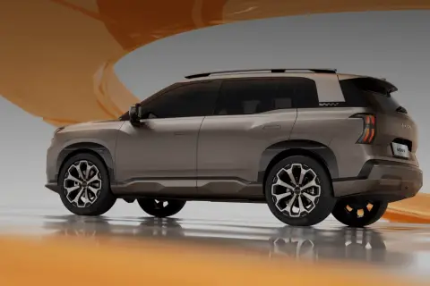Brązowy SUV GAC AION V z futurystycznymi światłami i felgami, prezentowany na tle pomarańczowej wstęgi.