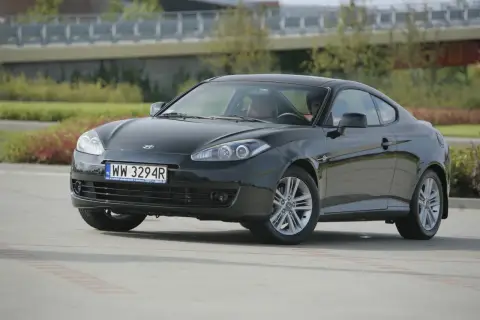 Czarny Hyundai Coupe 2.7 V6 z przyciemnionymi szybami i sportowymi felgami, zaparkowany na zewnątrz.