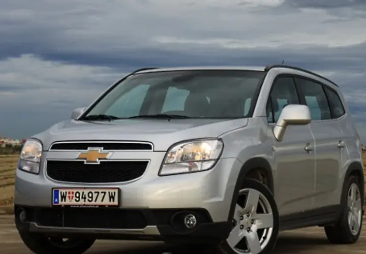 Srebrny Chevrolet Orlando na tle pochmurnego nieba i pól. Idealny na rodzinne wypady.