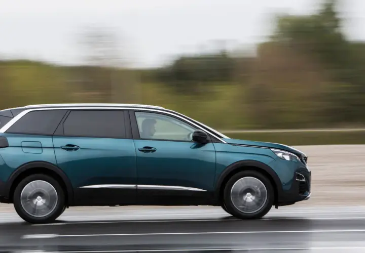 Turkusowy Peugeot 5008 2.0 HDI w ruchu, z rozmytym tłem.