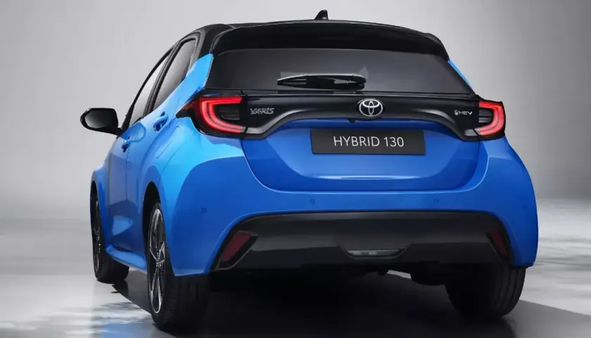 Niebieski hatchback Toyota Yaris IV z czarnym dachem i napisem HYBRID 130 z tyłu.