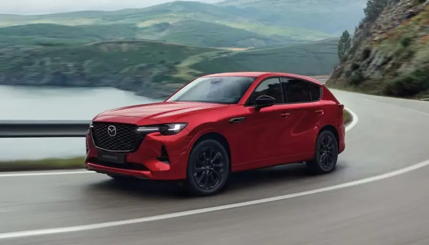 Czerwona Mazda CX-60 3.3 diesel pokonuje zakręt na malowniczej drodze.