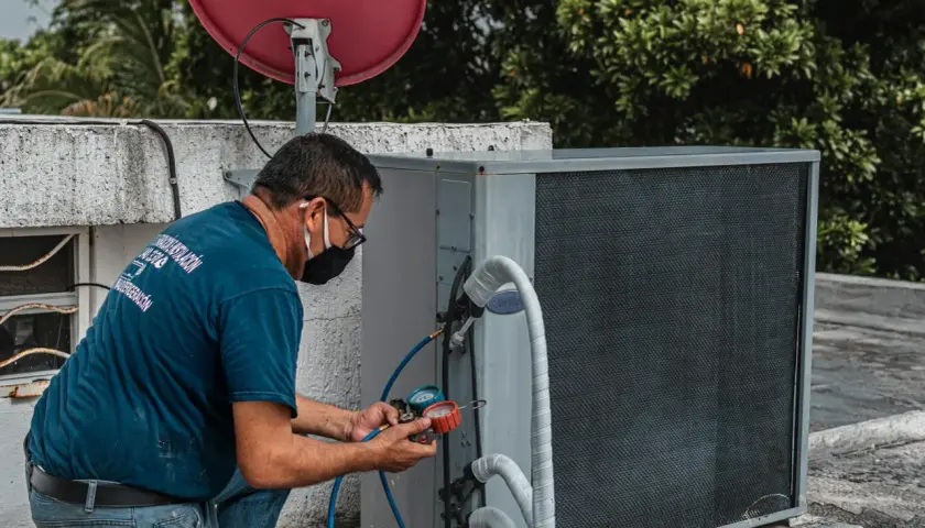 Technik sprawdza ciśnienie na zaworze rozprężnym klimatyzacji, używając manometrów.