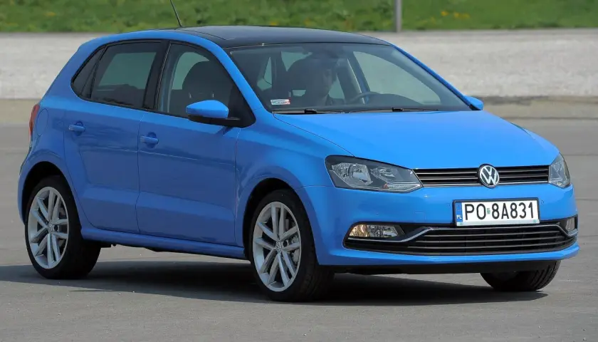 Niebieski VW Polo 2010 z czarnym dachem, zaparkowany na zewnątrz.