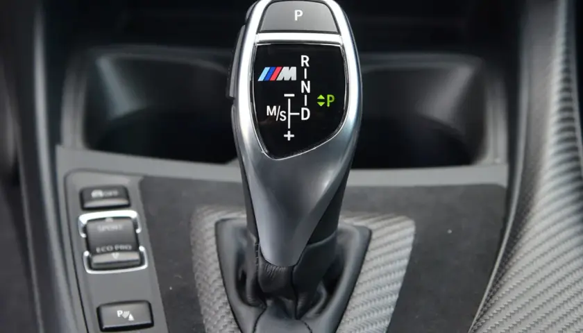 Oznaczenia automatycznej skrzyni biegów BMW M: P, R, N, D, M/S. Widoczny przycisk P i wybór trybów Sport/Eco Pro.