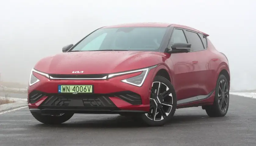 Czerwone Kia EV6 GT na mokrej drodze, w tle mgła.