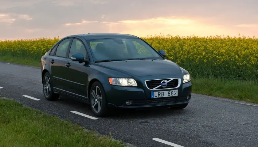Ciemnozielone Volvo S40 2.0 diesel jedzie wiejską drogą pośród kwitnącego rzepaku.