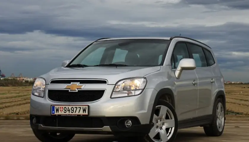 Srebrny Chevrolet Orlando na tle pochmurnego nieba i pól. Idealny na rodzinne wypady.