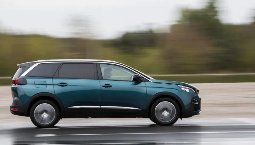 Turkusowy Peugeot 5008 2.0 HDI w ruchu, z rozmytym tłem.