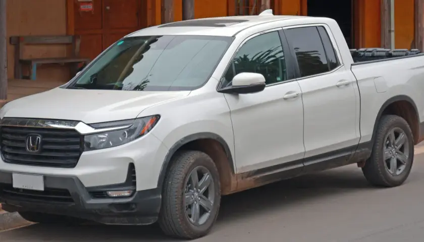 Biały Honda Ridgeline z błotem na progach, gotowy na przygodę.
