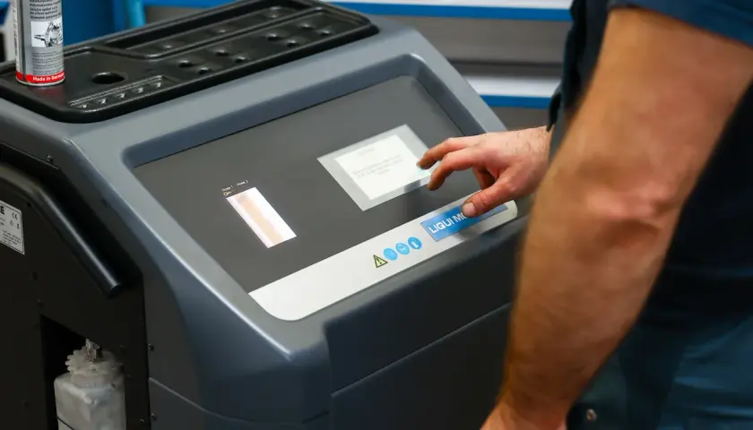 Mechanik dotyka ekranu maszyny do adaptacji skrzyni biegów, przygotowując ją do czyszczenia.