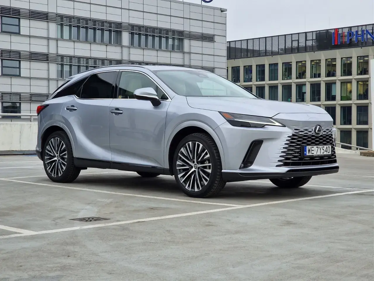 Srebrny Lexus 350 zaparkowany przed nowoczesnym budynkiem biurowym.