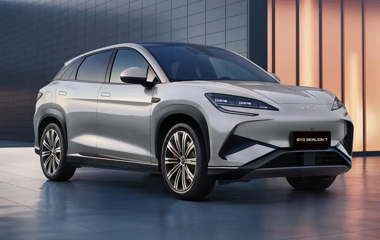 Elegancki, srebrny BYD Sealion 7 SUV stoi przed nowoczesnym budynkiem.
