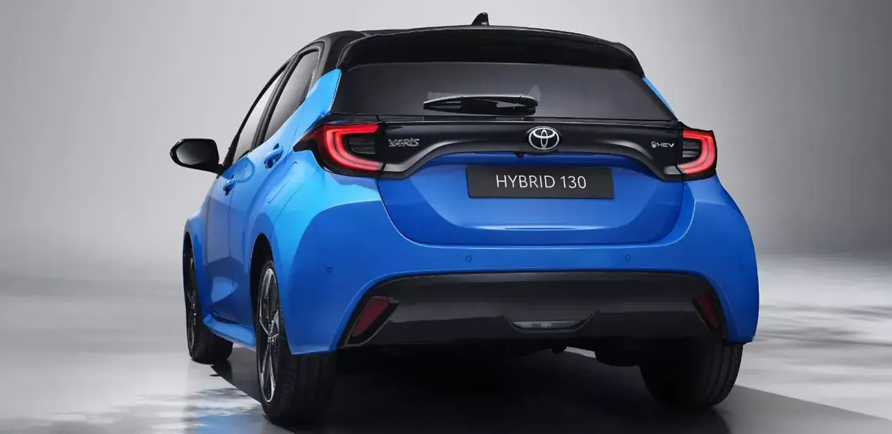 Niebieski hatchback Toyota Yaris IV z czarnym dachem i napisem HYBRID 130 z tyłu.