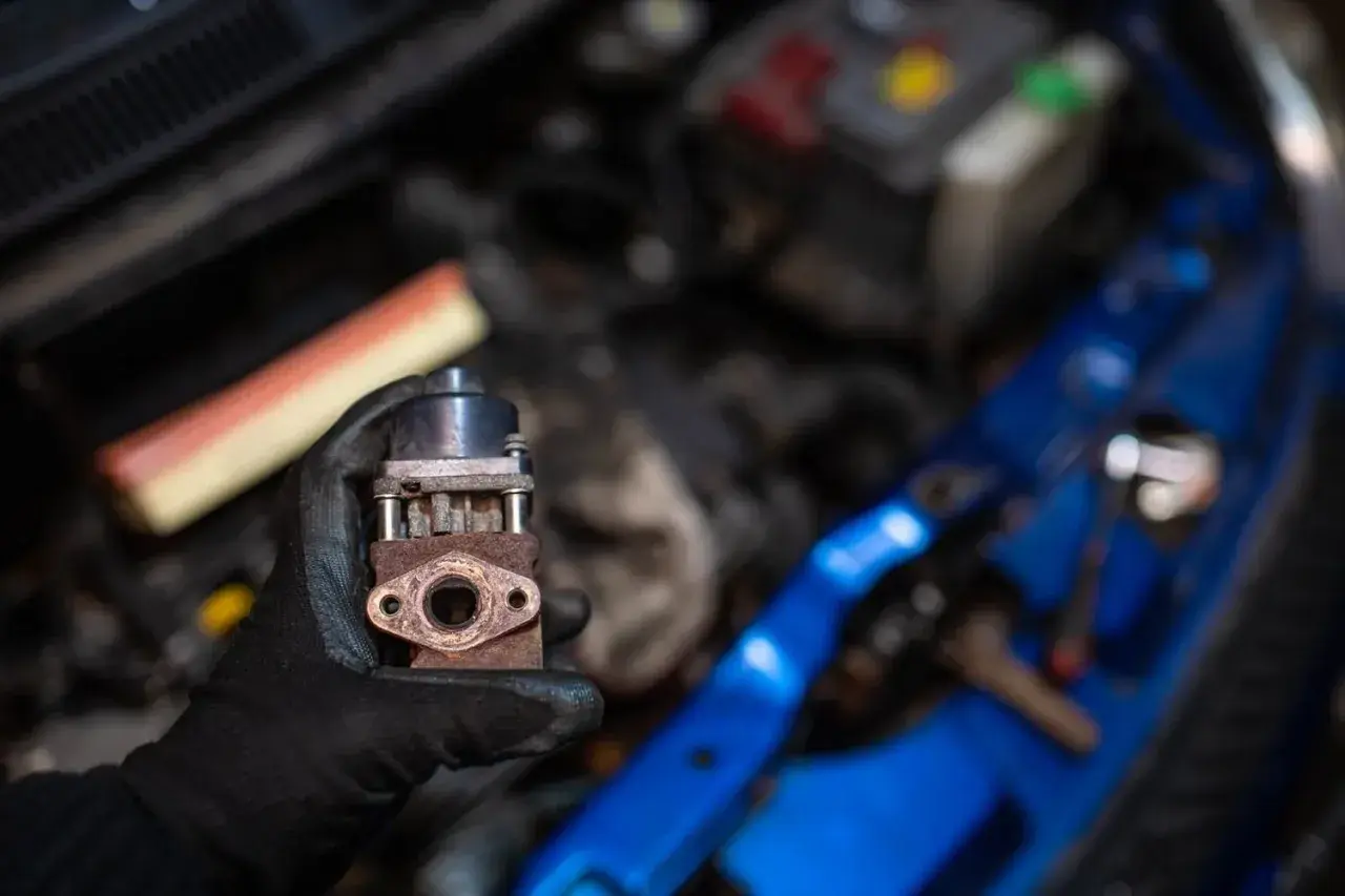 Zardzewiały zawór EGR w dłoni mechanika. Zepsuty EGR może powodować różne objawy, takie jak nierówna praca silnika czy zwiększone spalanie.