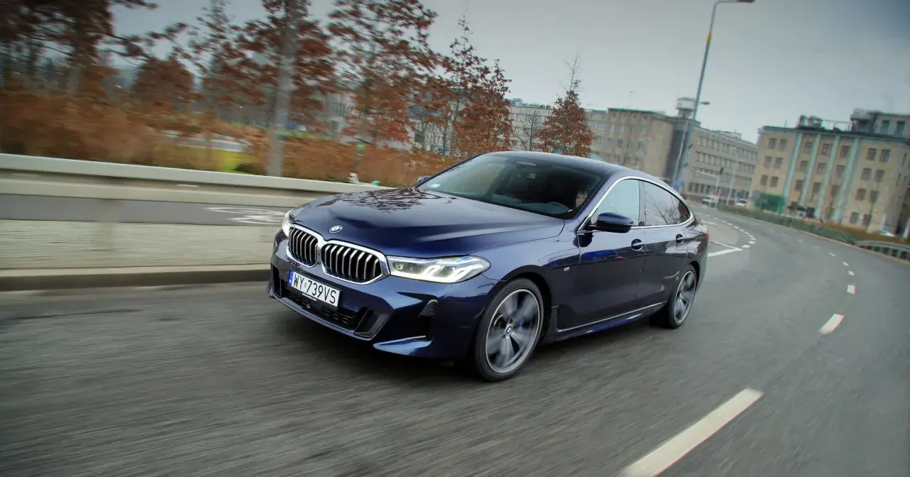 Granatowe BMW 640i sunie po miejskiej drodze, ukazując swoje eleganckie linie i sportowy charakter.