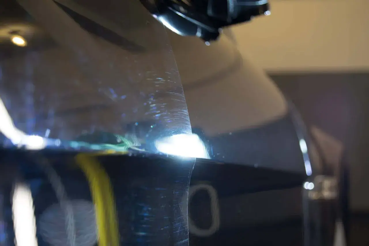Widoczne hologramy na lakierze samochodu, które ujawniają drobne rysy i niedoskonałości pod światłem.