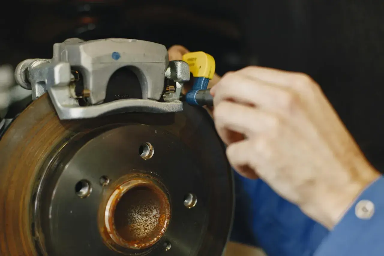 Mechanik pracuje nad tarczą hamulcową, sprawdzając stan układu hamulcowego.