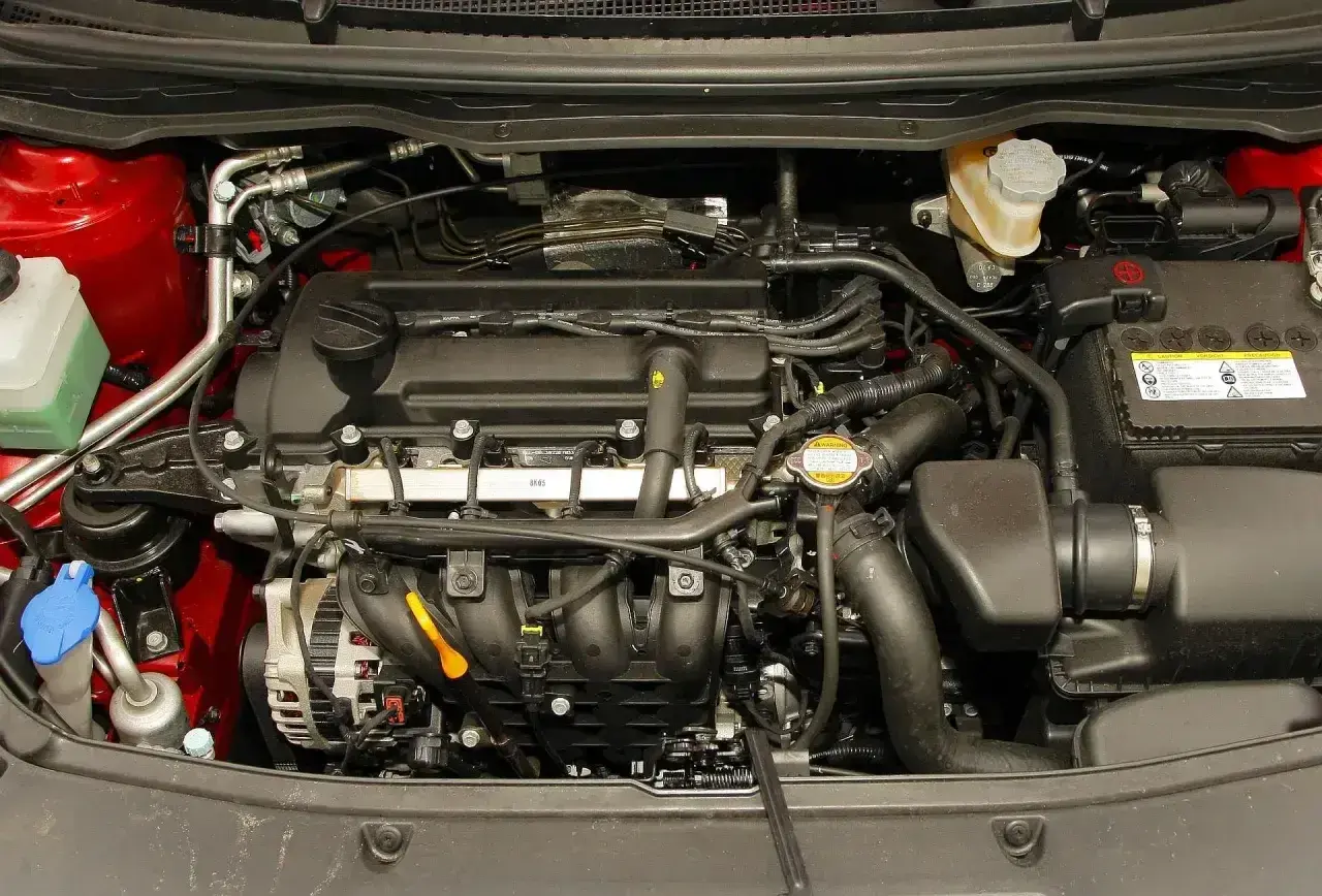 Silnik Hyundai i20 2010. Widoczny alternator, akumulator, płyny i przewody.