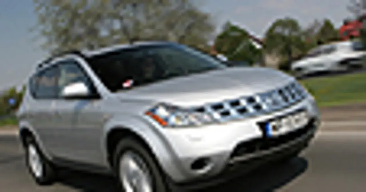 Srebrny Nissan Murano 3.5 V6 na drodze, z drzewami i innymi samochodami w tle.
