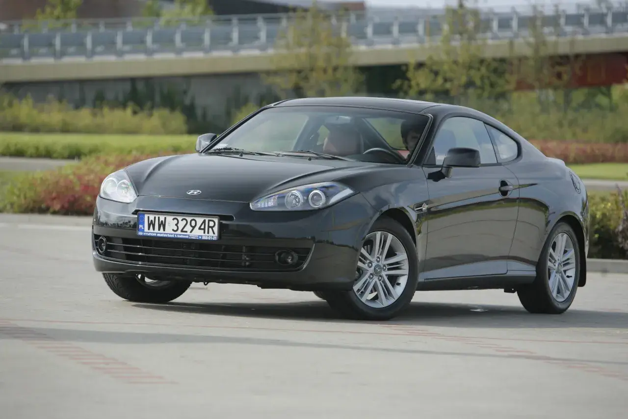 Czarny Hyundai Coupe 2.7 V6 z przyciemnionymi szybami i sportowymi felgami, zaparkowany na zewnątrz.