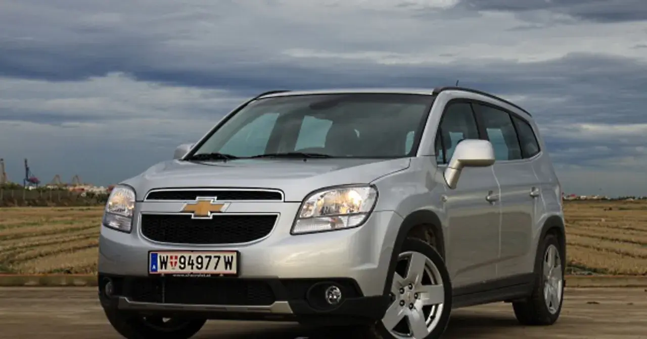 Srebrny Chevrolet Orlando na tle pochmurnego nieba i pól. Idealny na rodzinne wypady.
