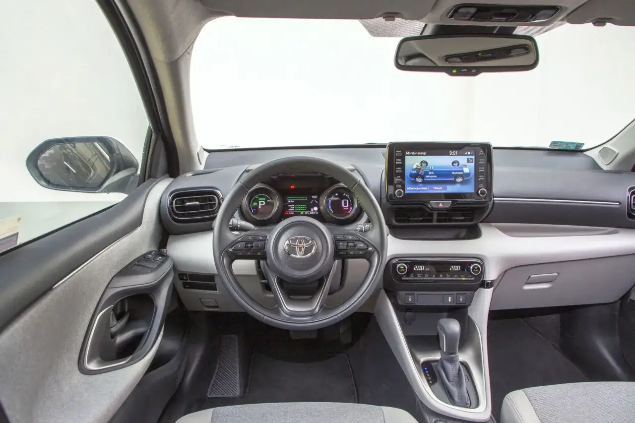 Wnętrze Toyoty Yaris IV z ekranem multimediów pokazującym monitor energii i cyfrowymi zegarami.