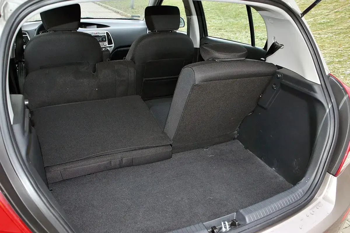 Wnętrze Hyundai i20 2010 z rozłożonymi tylnymi siedzeniami, tworzącymi płaską przestrzeń bagażową.