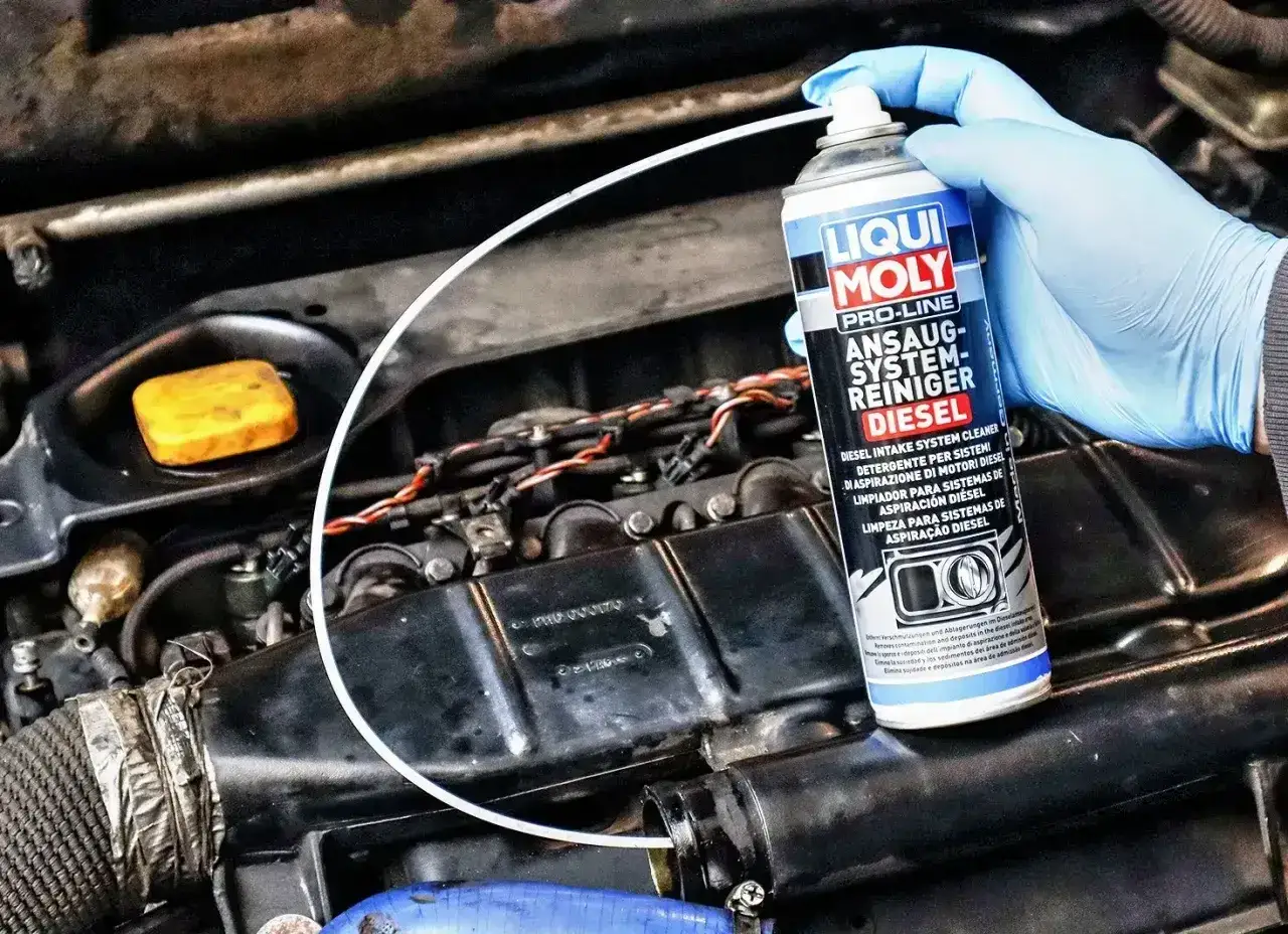 Ręka w niebieskiej rękawiczce aplikuje preparat Liqui Moly do czyszczenia układu dolotowego diesla, pokazując jak wyczyścić egr bez rozbierania.