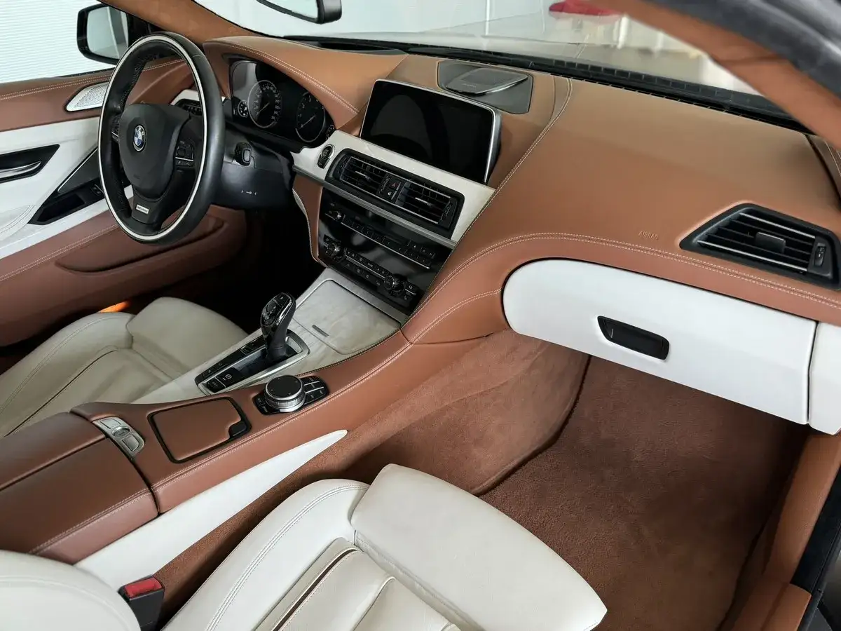 Wnętrze BMW 640i z brązową i białą skórą, drewnianymi wstawkami i nowoczesnym panelem sterowania.